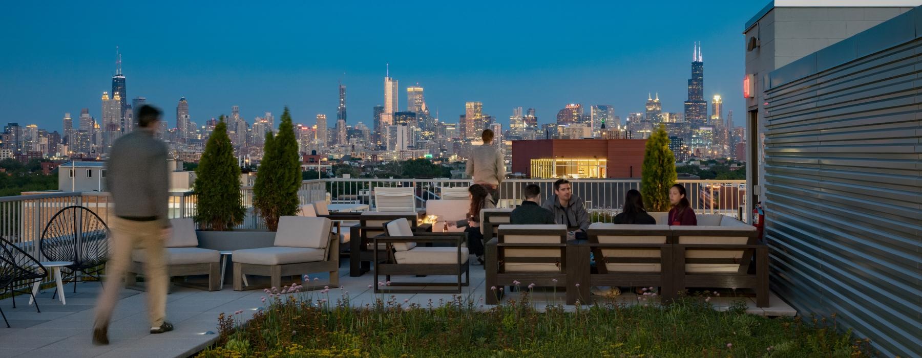 a group of people sitting at tables on a rooftop patio